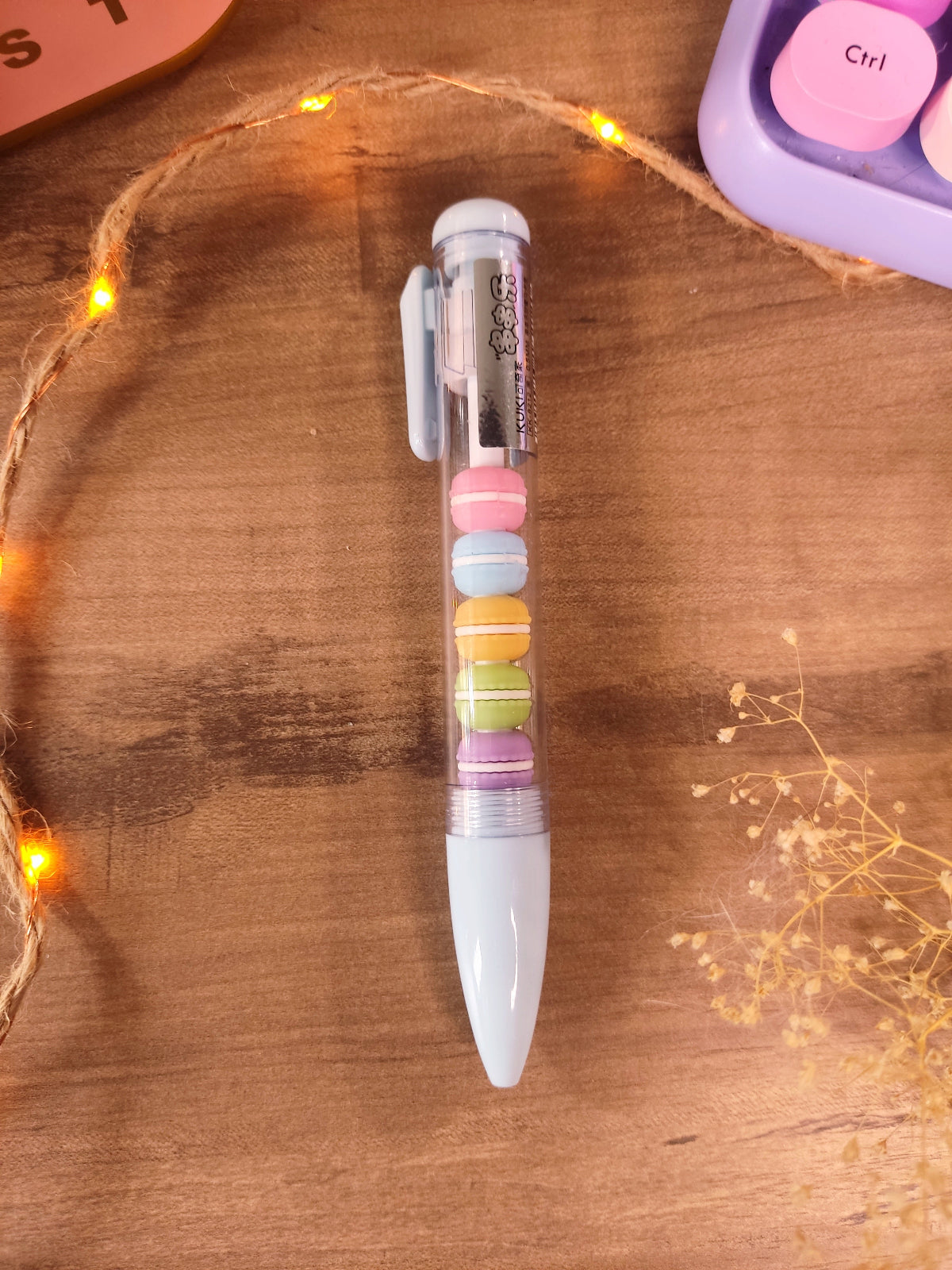 Stylo gel noir kawaii avec figurines de macarons pastel amovibles pour la rentrée.