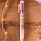 Stylo gel noir kawaii avec figurines de macarons pastel amovibles pour la rentrée.