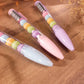 Stylo gel noir kawaii avec figurines de macarons pastel amovibles pour la rentrée.