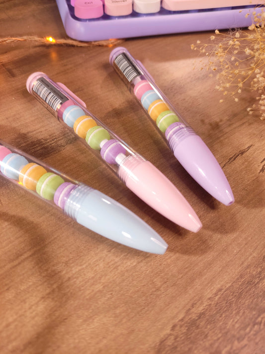 Stylo gel noir kawaii avec figurines de macarons pastel amovibles pour la rentrée.