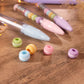 Détail des petites figurines macarons pastel interchangeables dans le stylo.