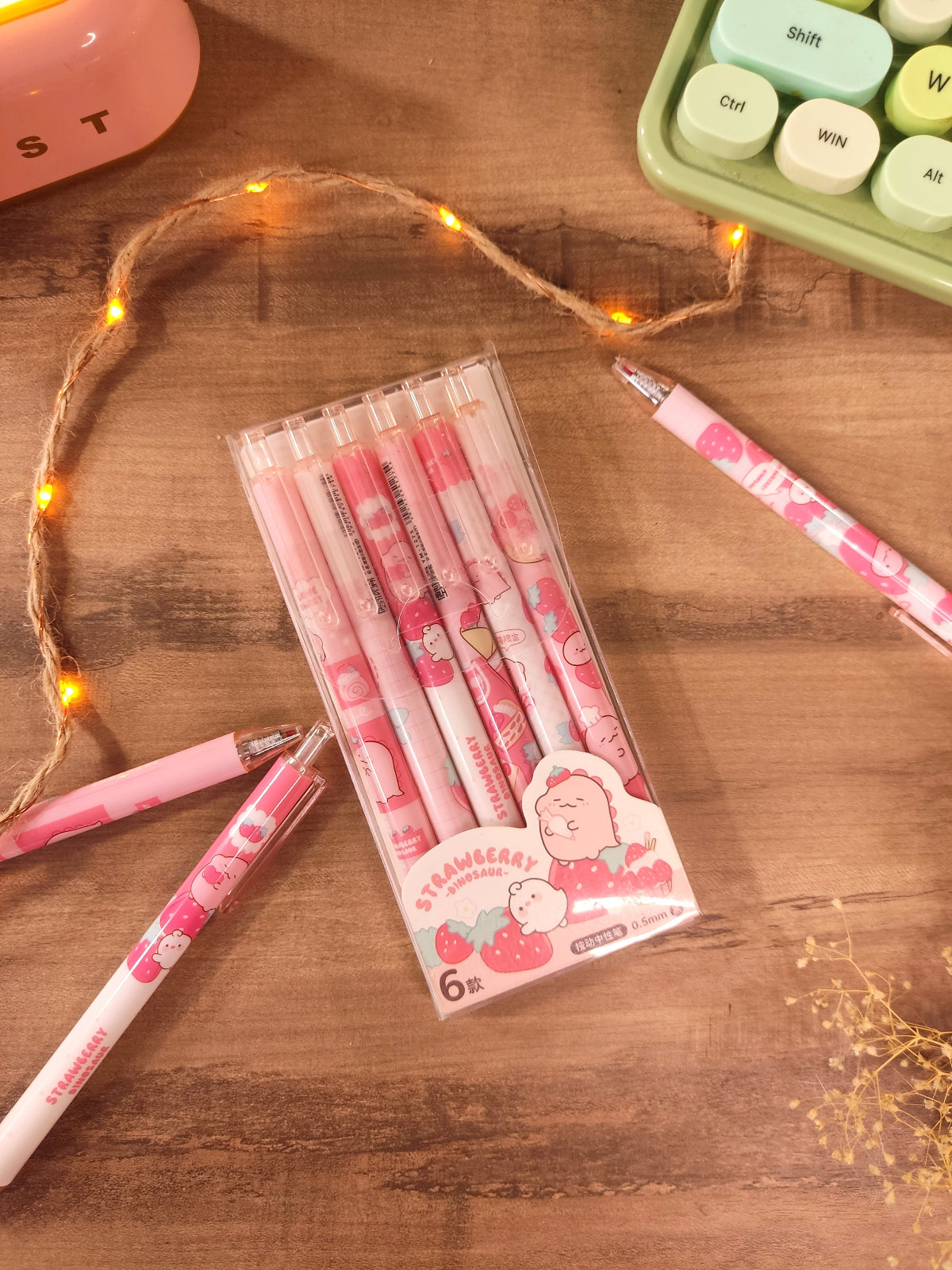Stylos dinosaures et fraises rangés dans une trousse d'école pour le collège et lycée.