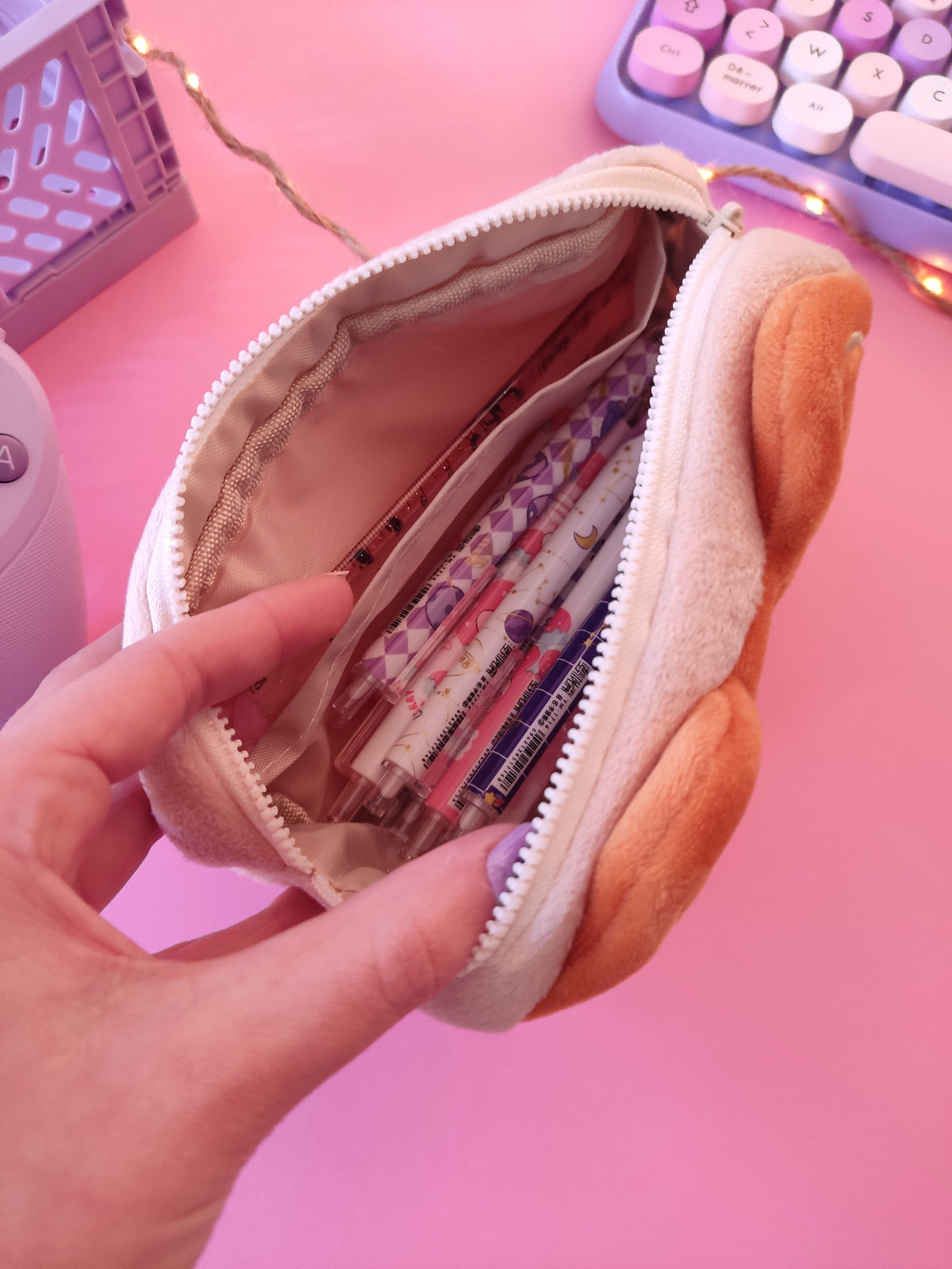 Compartiment de la trousse gâteau chat rempli de stylos et matériel scolaire.